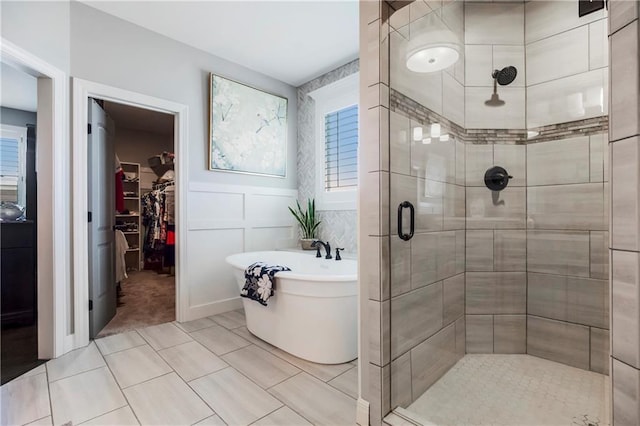 bathroom with a shower stall, a freestanding bath, and a spacious closet