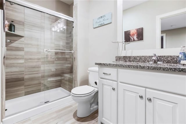 bathroom featuring toilet, a shower stall, and vanity
