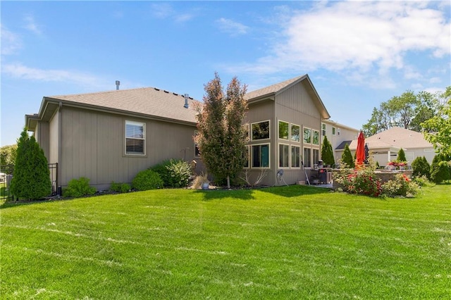 rear view of property featuring a lawn and roof with shingles