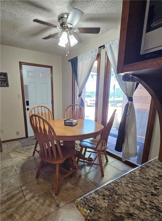 2500 N 10th St, Independence, KS 67301 - dining room with a textured ceiling, ceiling fan, baseboards, and stone finish floors