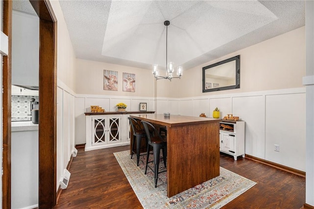 2018 Park Ln, Smithville, MO 64089 - bar area with dark wood-style floors, a decorative wall, wainscoting, a textured ceiling, and a chandelier