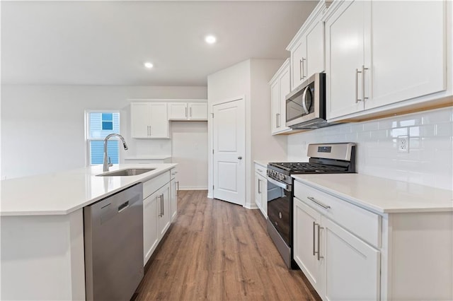 2114 Creek View Ln, Raymore, MO 64083 - kitchen featuring appliances with stainless steel finishes, a sink, wood finished floors, decorative backsplash, and white cabinets