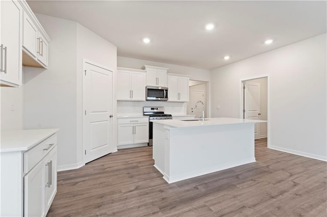 2114 Creek View Ln, Raymore, MO 64083 - kitchen with stainless steel appliances, a sink, wood finished floors, white cabinets, and recessed lighting