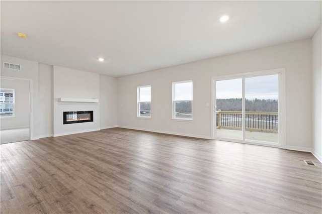 2114 Creek View Ln, Raymore, MO 64083 - unfurnished living room with wood finished floors, baseboards, a glass covered fireplace, and recessed lighting