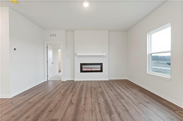 2114 Creek View Ln, Raymore, MO 64083 - unfurnished living room featuring wood finished floors, a glass covered fireplace, and baseboards