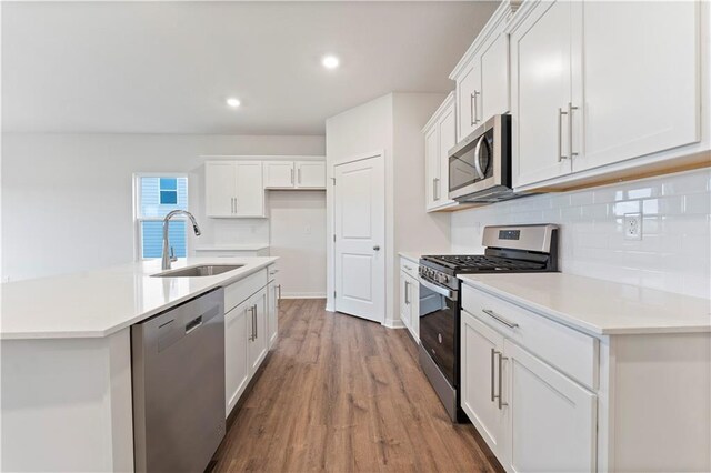 2114 Creek View Ln, Raymore, MO 64083 - kitchen featuring stainless steel appliances, a sink, wood finished floors, backsplash, and white cabinets