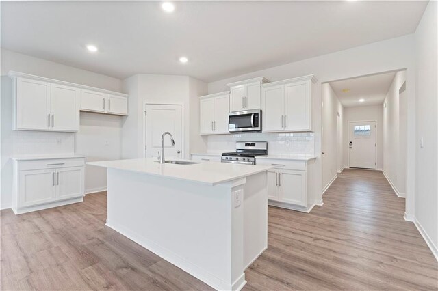 2114 Creek View Ln, Raymore, MO 64083 - kitchen with appliances with stainless steel finishes, a sink, a kitchen island with sink, light wood-style floors, and recessed lighting