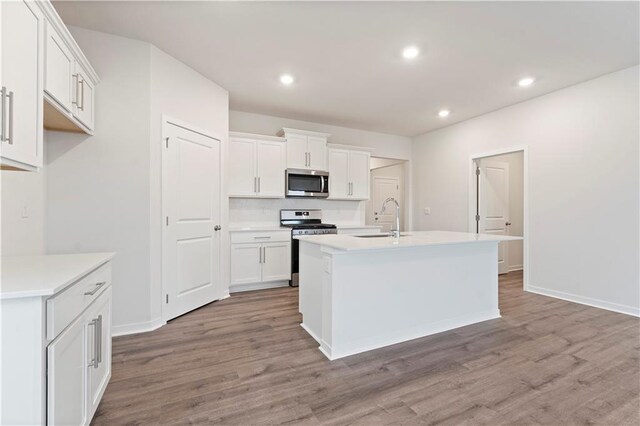 2114 Creek View Ln, Raymore, MO 64083 - kitchen featuring stainless steel appliances, a sink, wood finished floors, white cabinetry, and recessed lighting