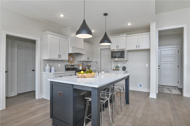 5854 Mccormick Dr, Shawnee, KS 66226 - kitchen with appliances with stainless steel finishes, white cabinets, light wood-style flooring, tasteful backsplash, and recessed lighting