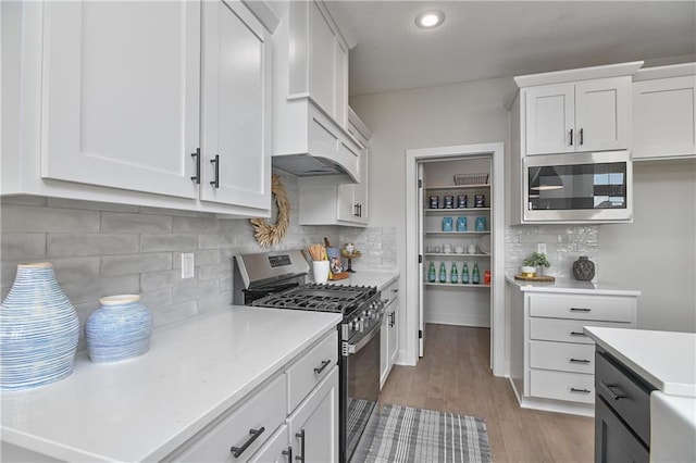 5854 Mccormick Dr, Shawnee, KS 66226 - kitchen with appliances with stainless steel finishes, light countertops, tasteful backsplash, light wood-type flooring, and white cabinetry