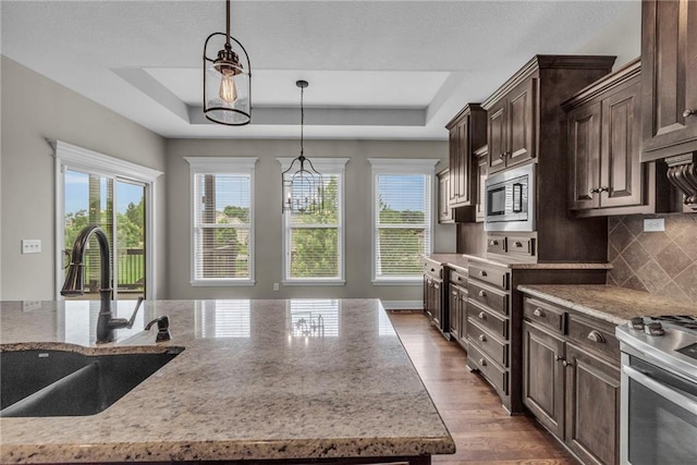 12750 N Arbor Way, Platte City, MO 64079 - kitchen with a sink, a raised ceiling, stainless steel appliances, dark brown cabinetry, and hanging light fixtures