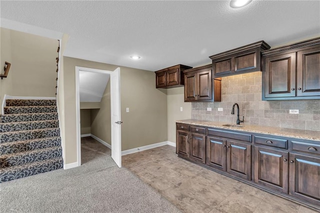 12750 N Arbor Way, Platte City, MO 64079 - kitchen featuring a sink, dark brown cabinetry, light stone counters, decorative backsplash, and a textured ceiling