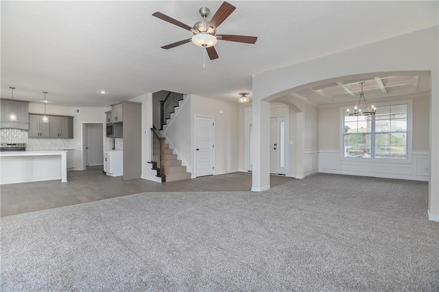 111 N Singletree St, Olathe, KS 66061 - unfurnished living room featuring a chandelier, carpet, a ceiling fan, arched walkways, and a wainscoted wall