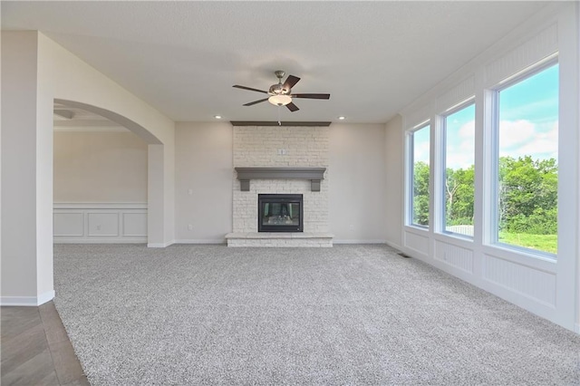 111 N Singletree St, Olathe, KS 66061 - unfurnished living room featuring a ceiling fan, carpet floors, a brick fireplace, and arched walkways