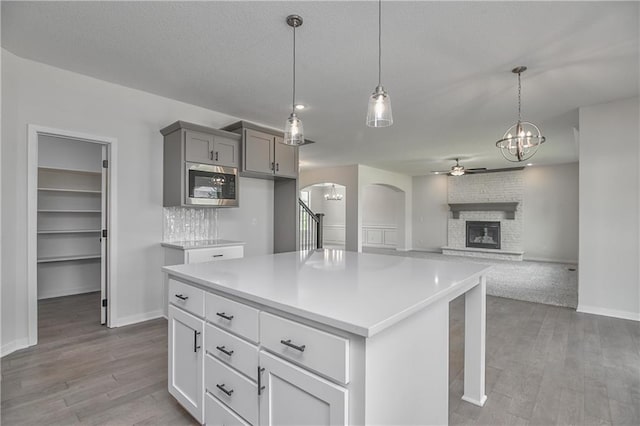 111 N Singletree St, Olathe, KS 66061 - kitchen with stainless steel microwave, ceiling fan, arched walkways, gray cabinetry, and light wood finished floors