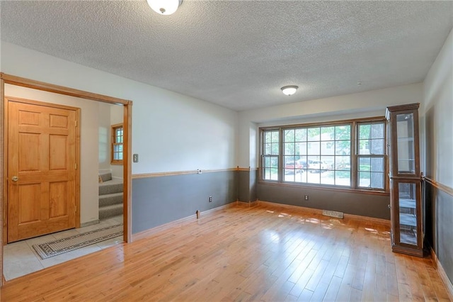 313 SW Ensley Ln, Lees Summit, MO 64081 - empty room featuring hardwood / wood-style floors, a textured ceiling, baseboards, and stairway