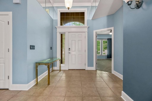 tiled foyer with baseboards, ceiling fan, and crown molding