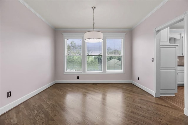 unfurnished dining area featuring wood finished floors, crown molding, and baseboards
