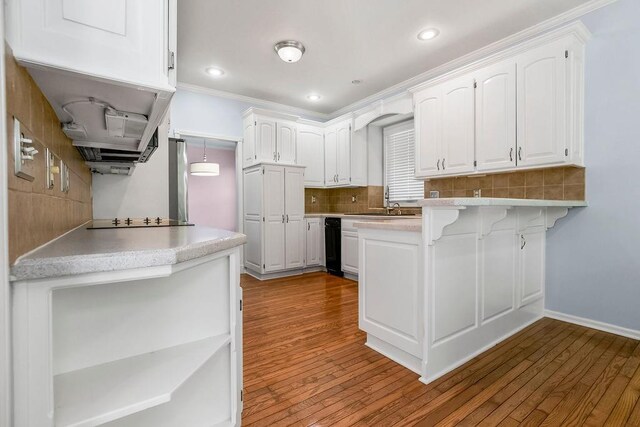 kitchen with a peninsula, wood finished floors, tasteful backsplash, white cabinets, and a breakfast bar area