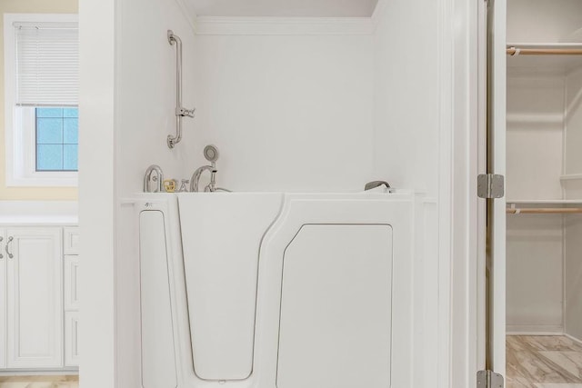 bathroom featuring a bathtub and crown molding