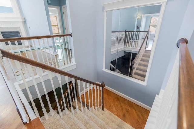 staircase with wood finished floors, baseboards, and plenty of natural light