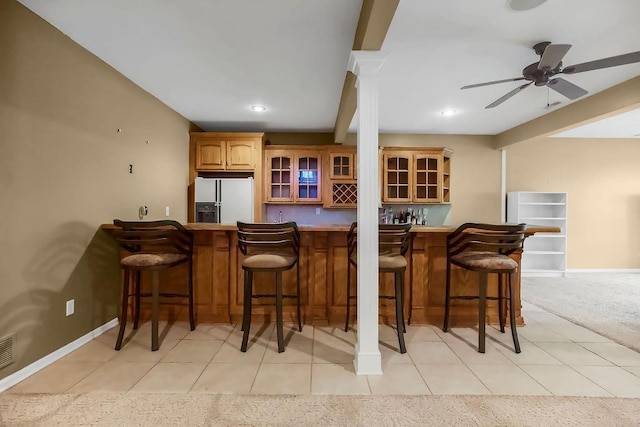 indoor wet bar with white fridge with ice dispenser, light tile patterned floors, decorative columns, baseboards, and recessed lighting