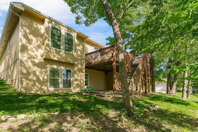 rear view of house featuring a wooden deck and a lawn