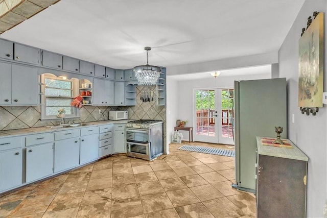 kitchen with open shelves, stainless steel appliances, backsplash, a chandelier, and french doors