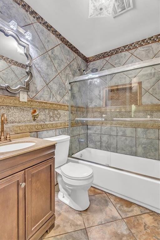 full bathroom with vanity, shower / bath combination with glass door, toilet, and tile patterned flooring