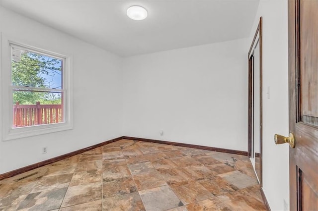 empty room with baseboards and stone finish floors