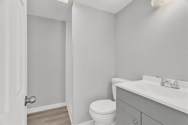 bathroom featuring vanity, wood finished floors, toilet, and baseboards
