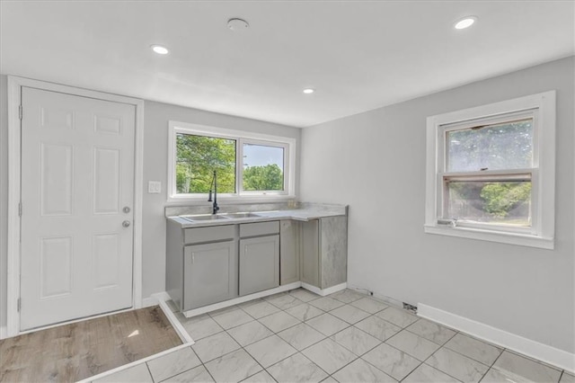kitchen with a sink, gray cabinetry, light countertops, recessed lighting, and baseboards