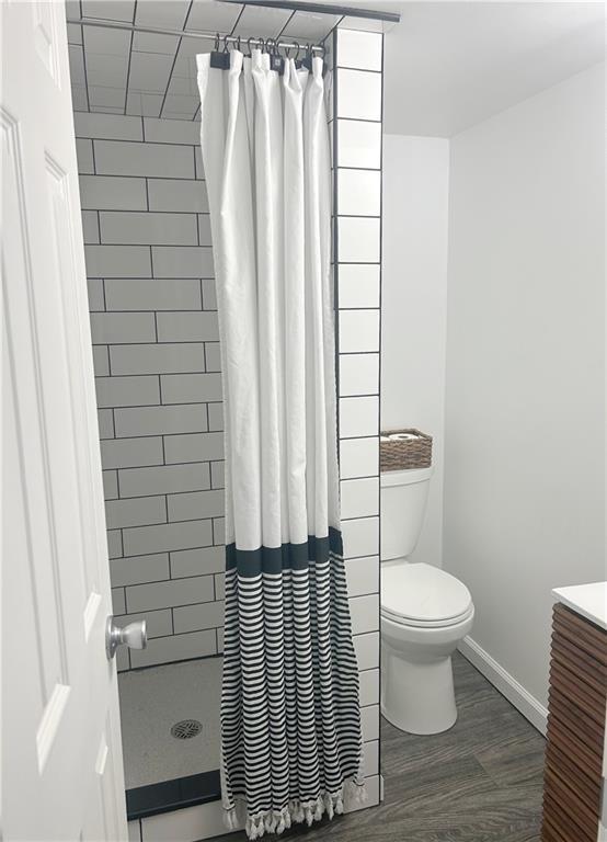 1919 Seneca St, Leavenworth, KS 66048 - full bath with a shower with curtain, toilet, baseboards, vanity, and wood finished floors