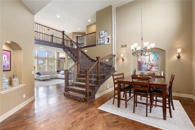 25205 W 97th Ter, Lenexa, KS 66227 - dining space with a chandelier, a high ceiling, stairway, arched walkways, and wood finished floors