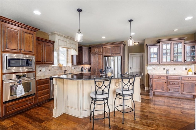25205 W 97th Ter, Lenexa, KS 66227 - kitchen with stainless steel appliances, backsplash, a kitchen bar, dark wood finished floors, and a center island