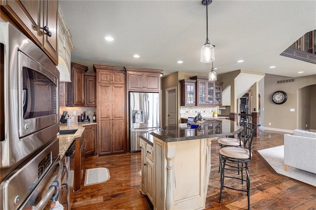 25205 W 97th Ter, Lenexa, KS 66227 - kitchen with appliances with stainless steel finishes, decorative backsplash, a kitchen island, recessed lighting, and glass insert cabinets