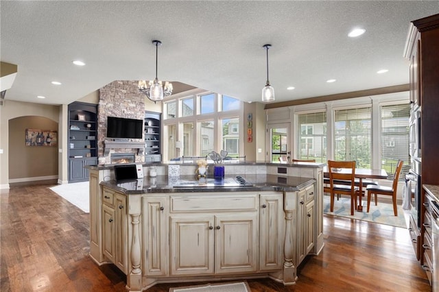25205 W 97th Ter, Lenexa, KS 66227 - kitchen featuring cream cabinetry, arched walkways, a textured ceiling, open floor plan, and wood finished floors