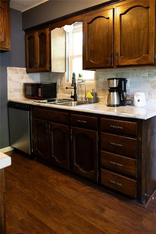 108 N Evanston Ave, Independence, MO 64053 - kitchen with black microwave, stainless steel dishwasher, light countertops, a sink, and decorative backsplash