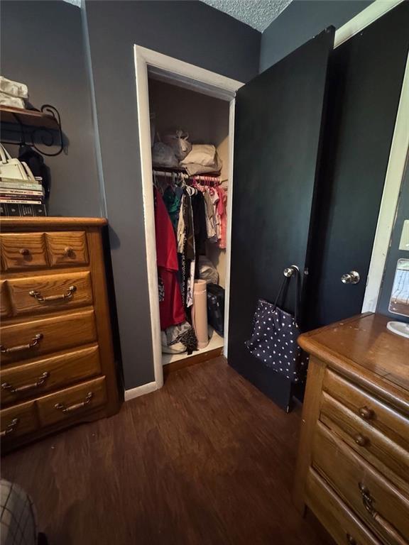 108 N Evanston Ave, Independence, MO 64053 - bedroom featuring dark wood-style floors, a walk in closet, a closet, and a textured ceiling