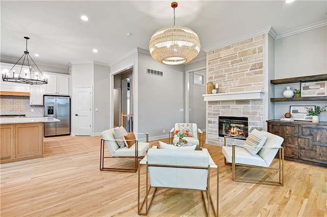 11349 Buena Vista St, Leawood, KS 66211 - living room featuring a chandelier, light wood-style flooring, a stone fireplace, crown molding, and recessed lighting