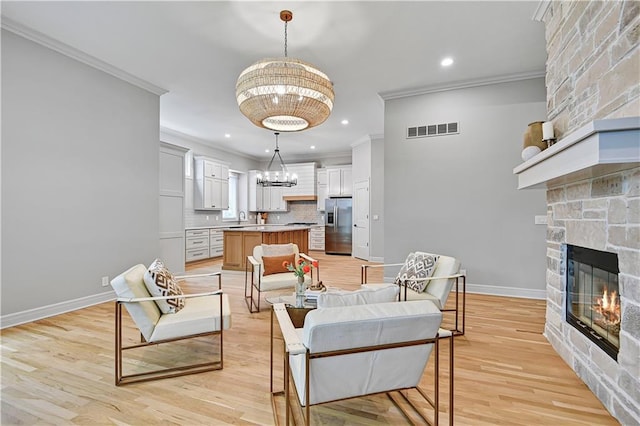 11349 Buena Vista St, Leawood, KS 66211 - living area featuring ornamental molding, a chandelier, a fireplace, light wood-type flooring, and baseboards