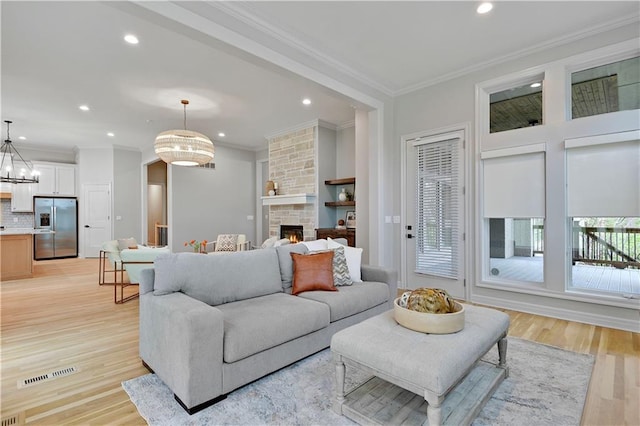 11349 Buena Vista St, Leawood, KS 66211 - living area with a fireplace, ornamental molding, recessed lighting, light wood-style flooring, and a chandelier