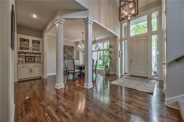 14814 Sherwood St, Leawood, KS 66224 - entrance foyer featuring a chandelier, ornate columns, dark wood-style floors, and baseboards