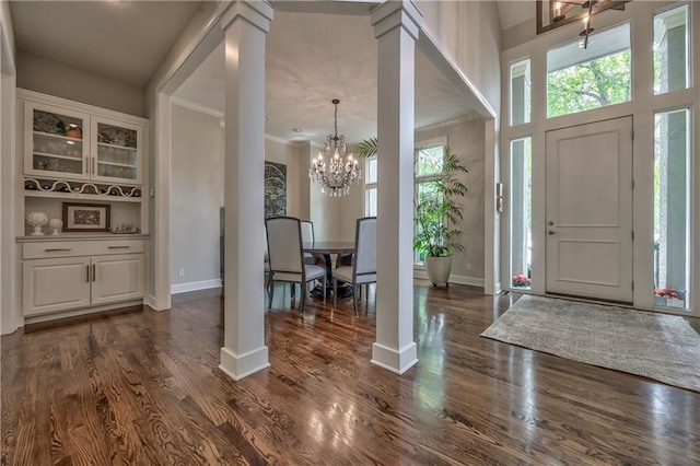 14814 Sherwood St, Leawood, KS 66224 - foyer entrance with a chandelier, dark wood-type flooring, crown molding, ornate columns, and baseboards