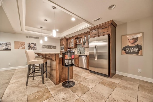 14814 Sherwood St, Leawood, KS 66224 - kitchen featuring built in appliances, a raised ceiling, a kitchen breakfast bar, tasteful backsplash, and decorative light fixtures