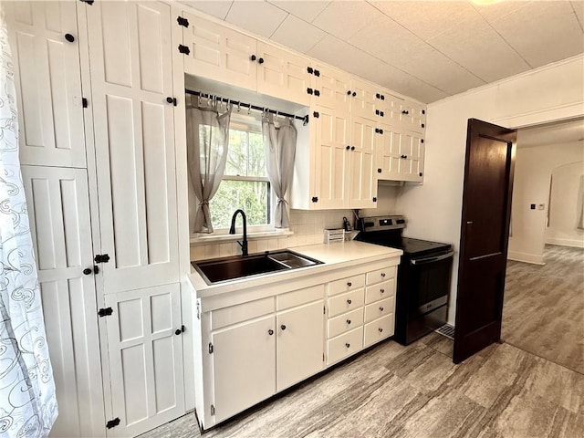 803 N Mulberry St, Maryville, MO 64468 - kitchen with stainless steel electric range, a sink, light wood-style floors, and white cabinetry
