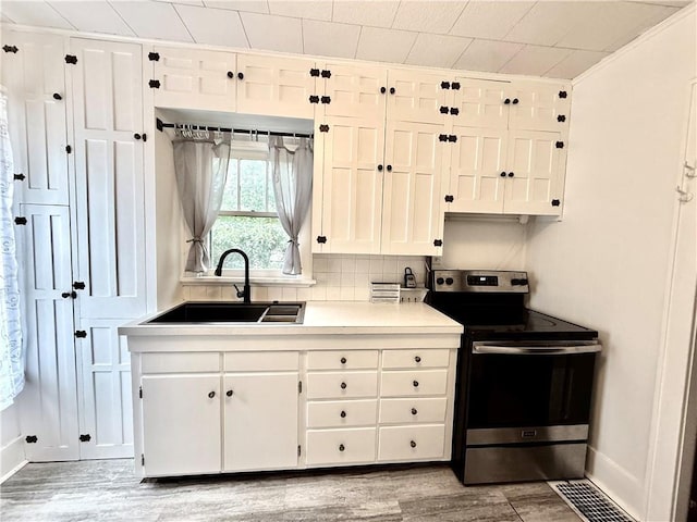 803 N Mulberry St, Maryville, MO 64468 - kitchen with electric stove, a sink, white cabinetry, light wood-style flooring, and light countertops