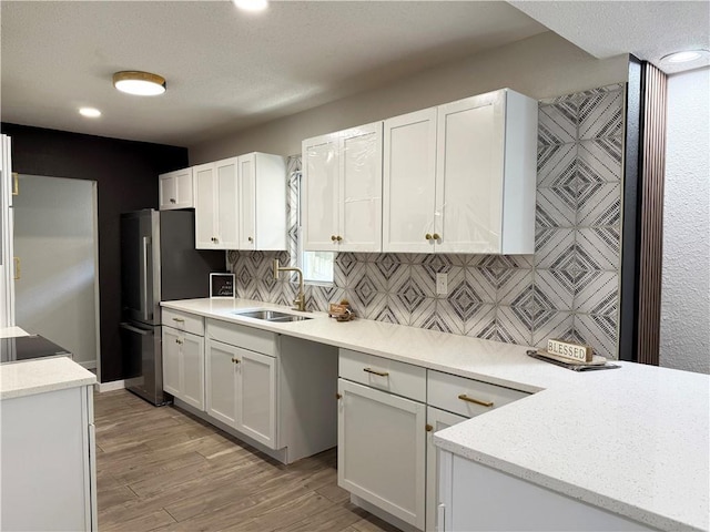 5715 Forest Ave, Kansas City, MO 64110 - kitchen with freestanding refrigerator, white cabinetry, tasteful backsplash, recessed lighting, and light wood-type flooring