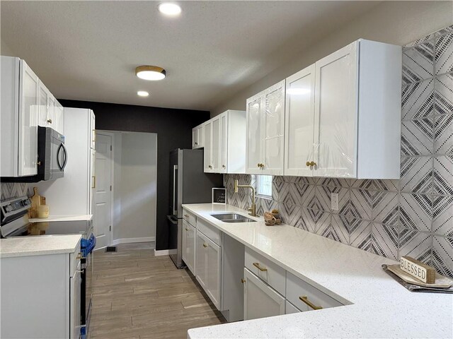 5715 Forest Ave, Kansas City, MO 64110 - kitchen featuring appliances with stainless steel finishes, backsplash, white cabinets, light wood-style flooring, and recessed lighting