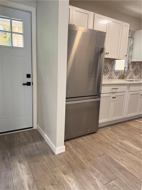5715 Forest Ave, Kansas City, MO 64110 - kitchen featuring freestanding refrigerator, light countertops, white cabinetry, and light wood finished floors